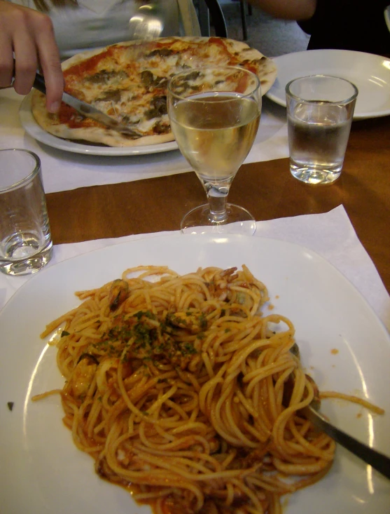 a plate of pasta and glasses of water sit on the table