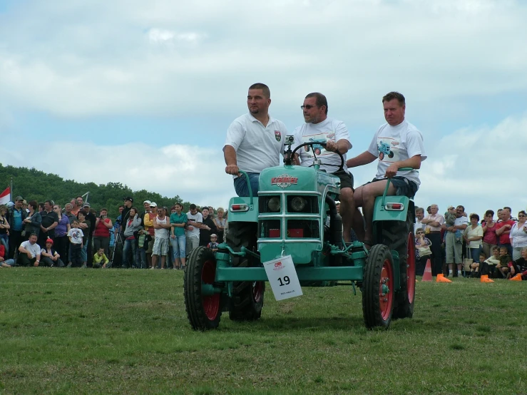 three men sitting on the back of a tractor