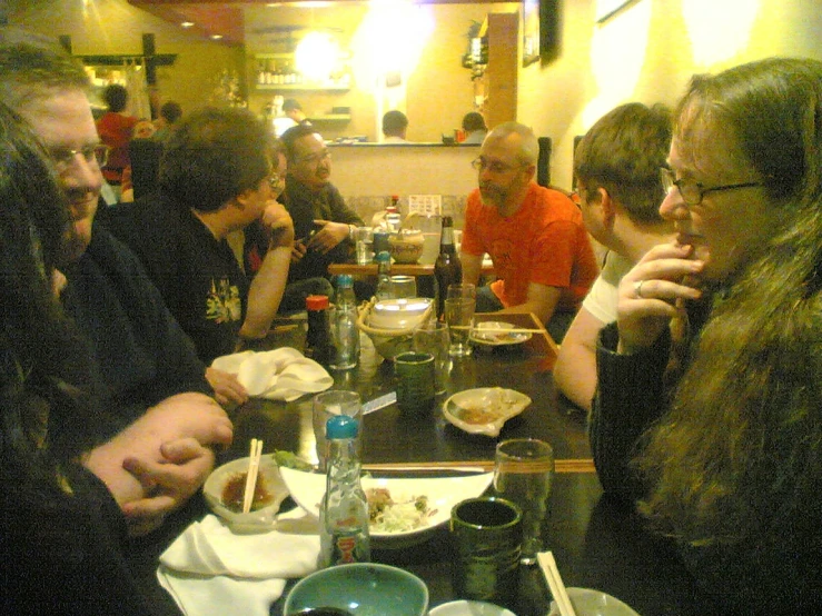 a group of people sitting at a restaurant table with food on them