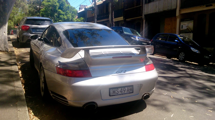 a silver car is parked at the curb in front of a building