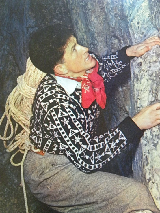 a man sitting next to some rocks with a red tie