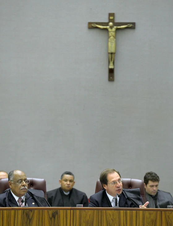 a man in suit sitting in front of a wooden table