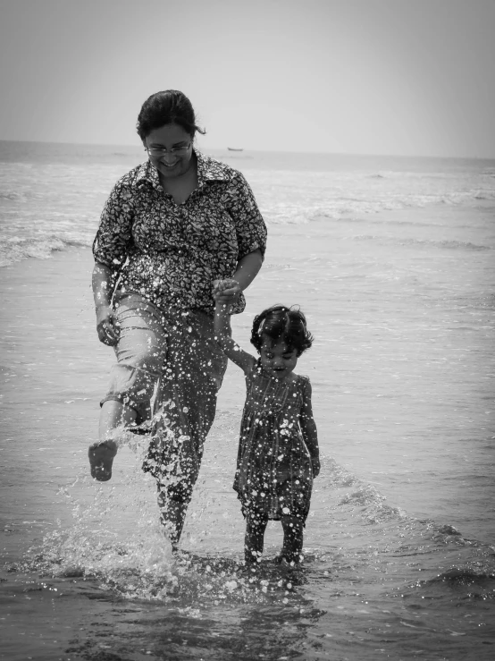 woman and child standing in the water on a beach