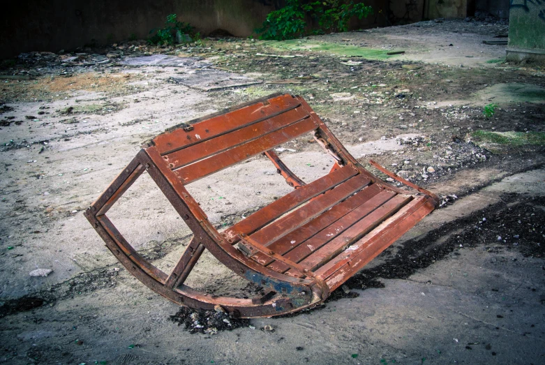 an abandoned wooden chair that is laying on the ground