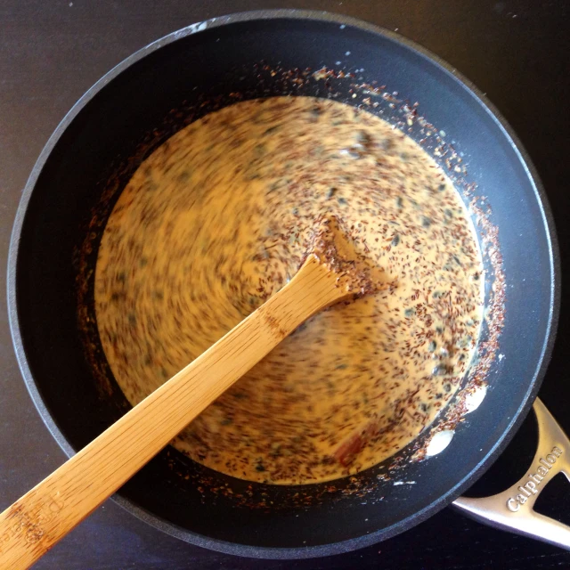 the pan is holding the dish that has a wooden spoon in it