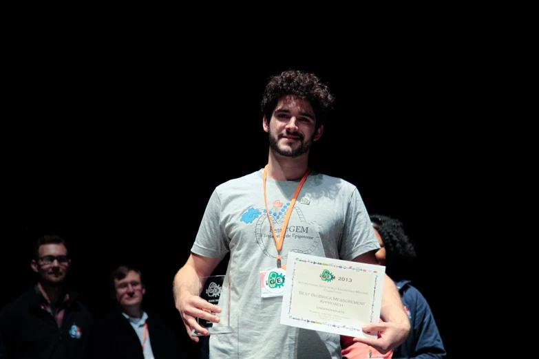 a man holding up an award on stage with other people watching