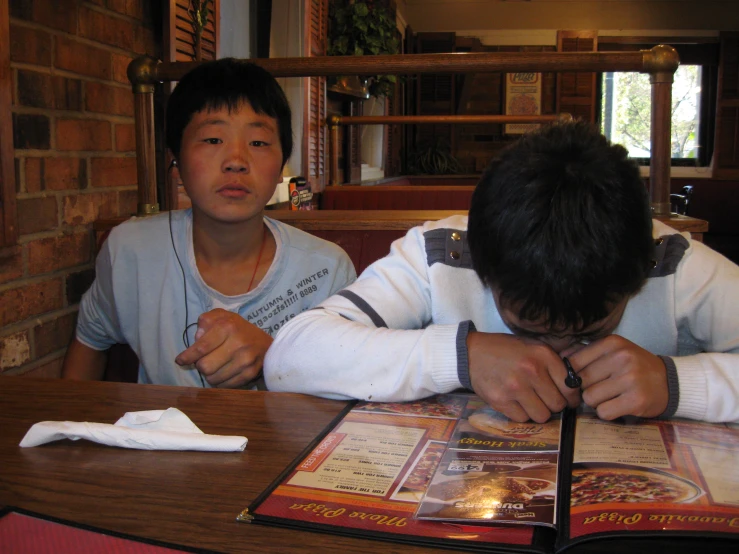 a young man sitting next to another man at a table