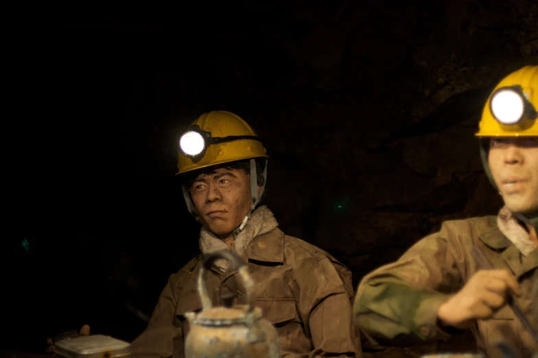 two men in yellow helmets and overalls sitting next to each other