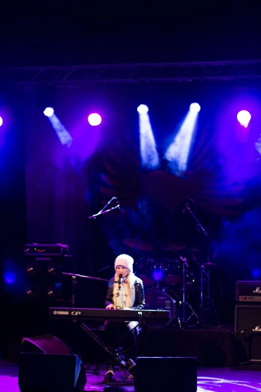 a woman is playing the keyboard and singing on stage