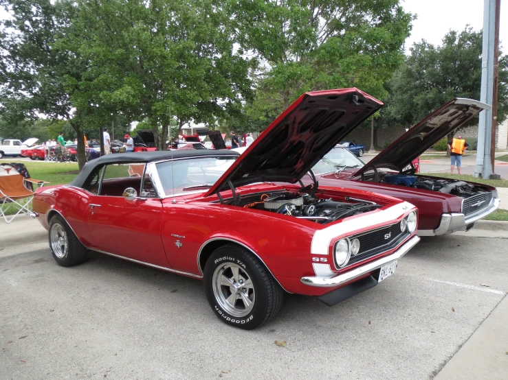 a red car is in the parking lot with its hood open