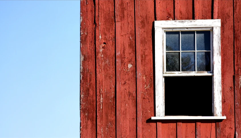 an old red building has a window and sky view