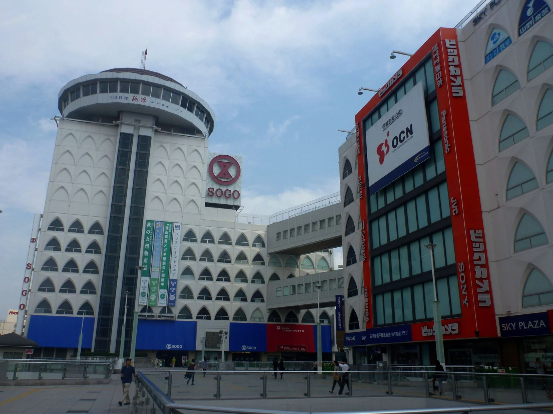 people walk around in front of the two buildings