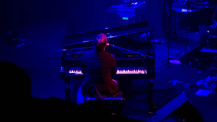 man playing piano on stage in front of many people