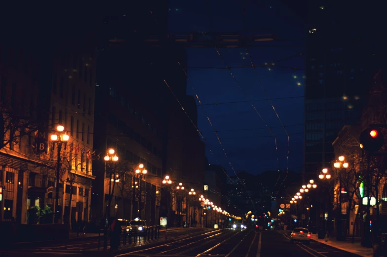 a dark street is lit up by lamps on poles