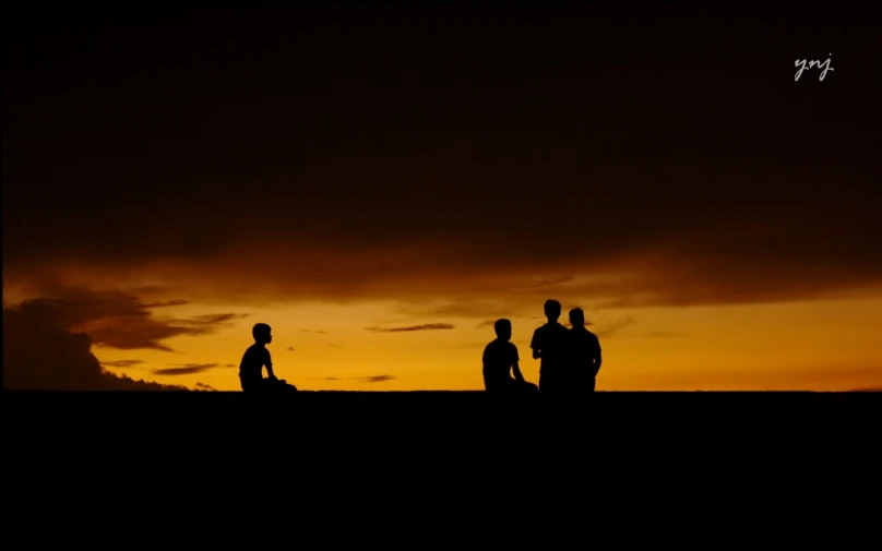 three people stand in the dark against a darkening sky