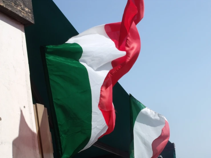 a close up s of three italian flags flying in the wind
