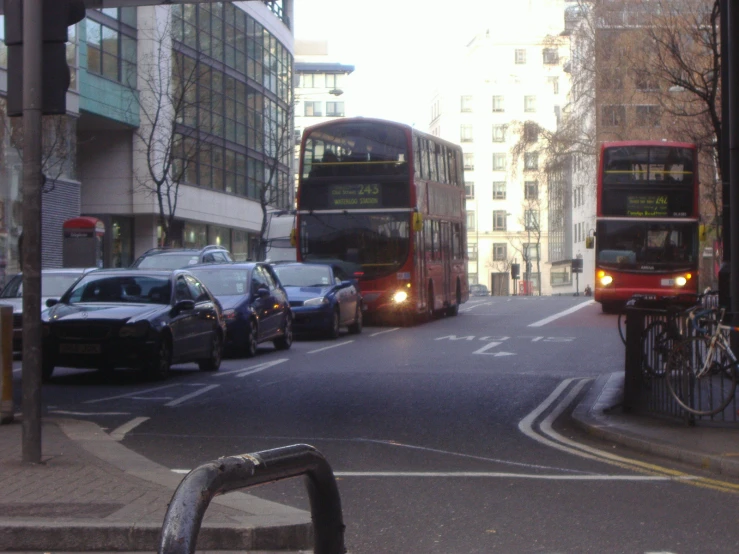 double decker bus driving down the road with cars and buses parked on it