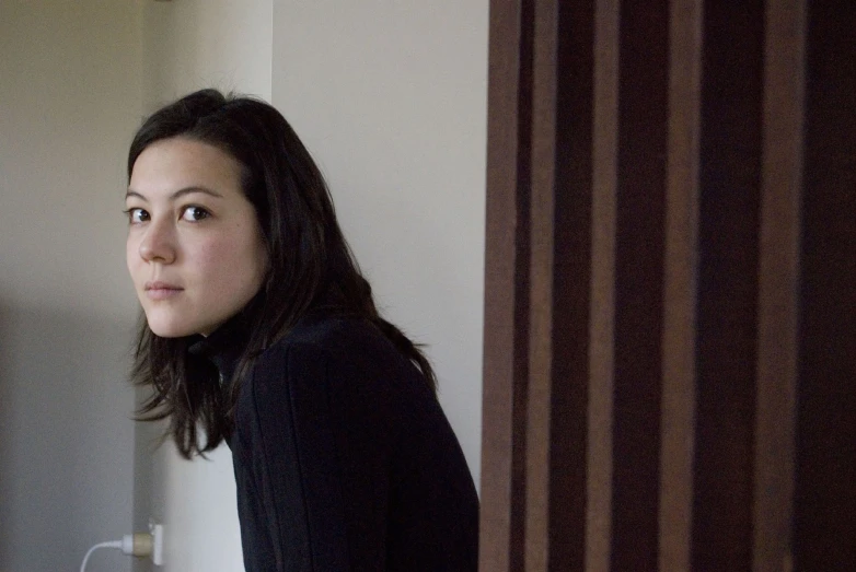 a woman standing in the corner with her hand on her waist