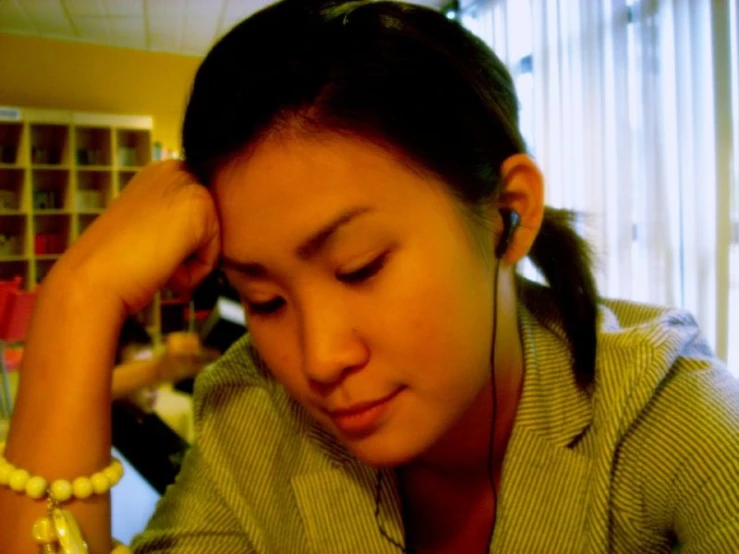 a woman wearing a white necklace has her hands behind her head