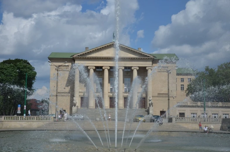 water is shooting out of a building while people look on