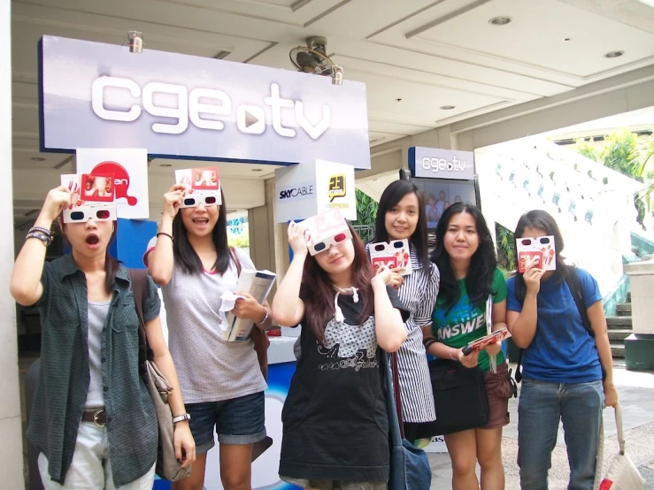 group of women wearing 3d glasses and standing in front of a sign