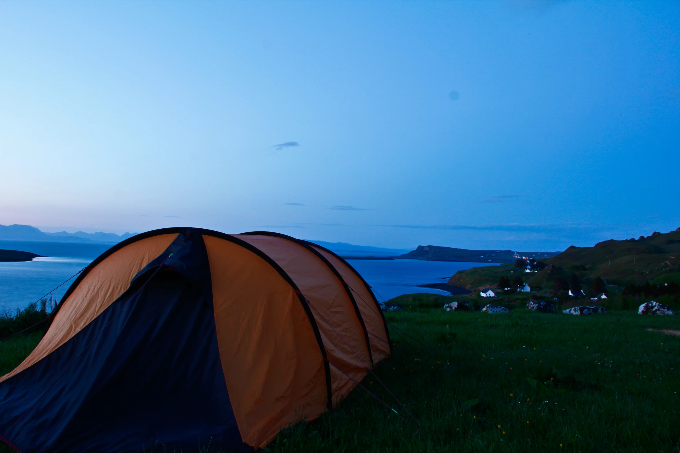 a tent sits on the grass overlooking an island