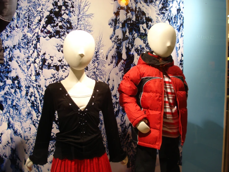 a mannequins dressed up in winter clothing in front of a snow mural