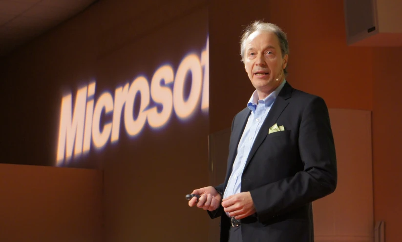 a man in a black suit is speaking on stage