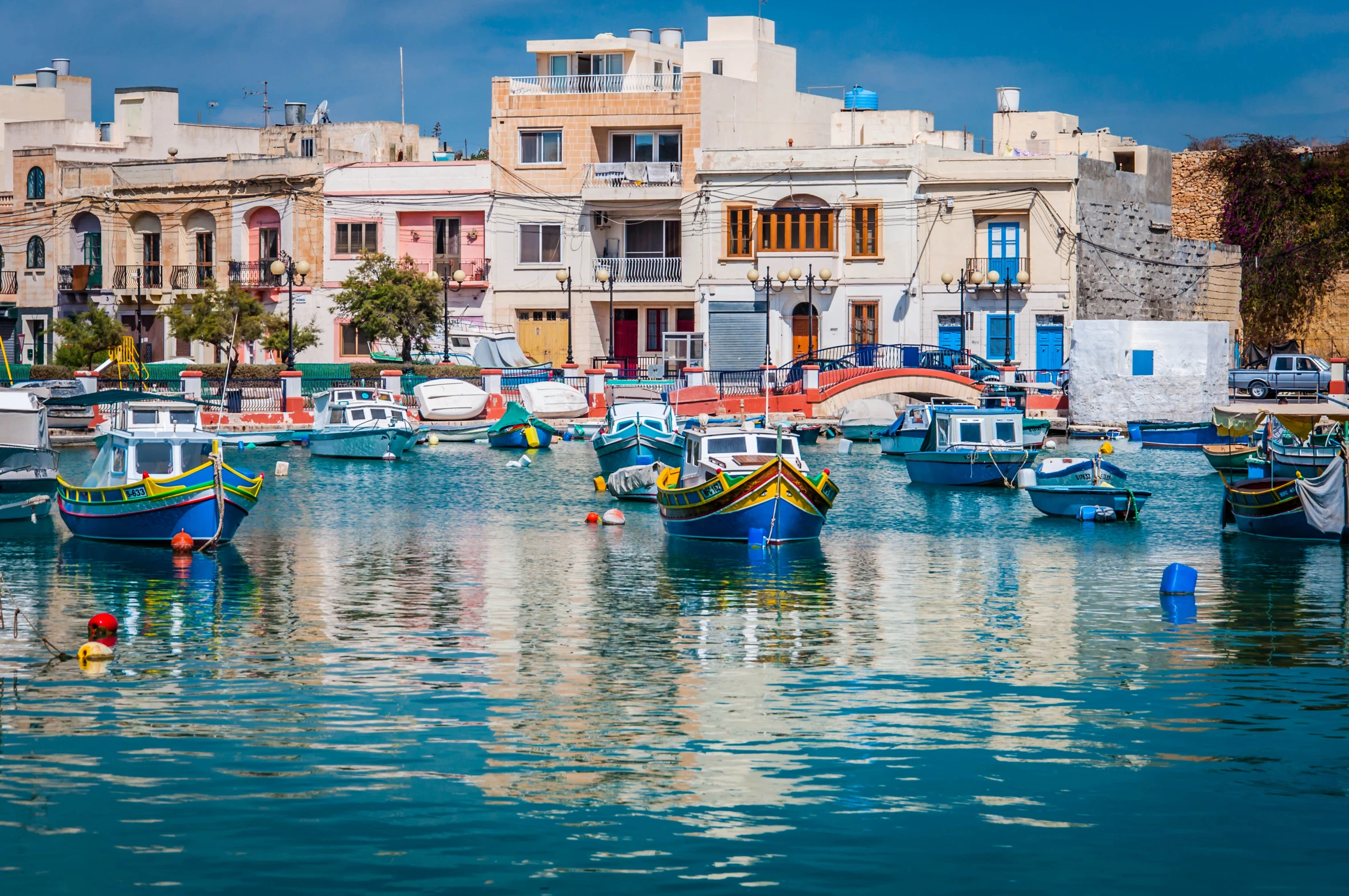 many different boats floating in the water near some buildings