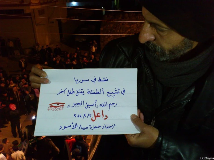 a man holds a sign as people watch from the balcony