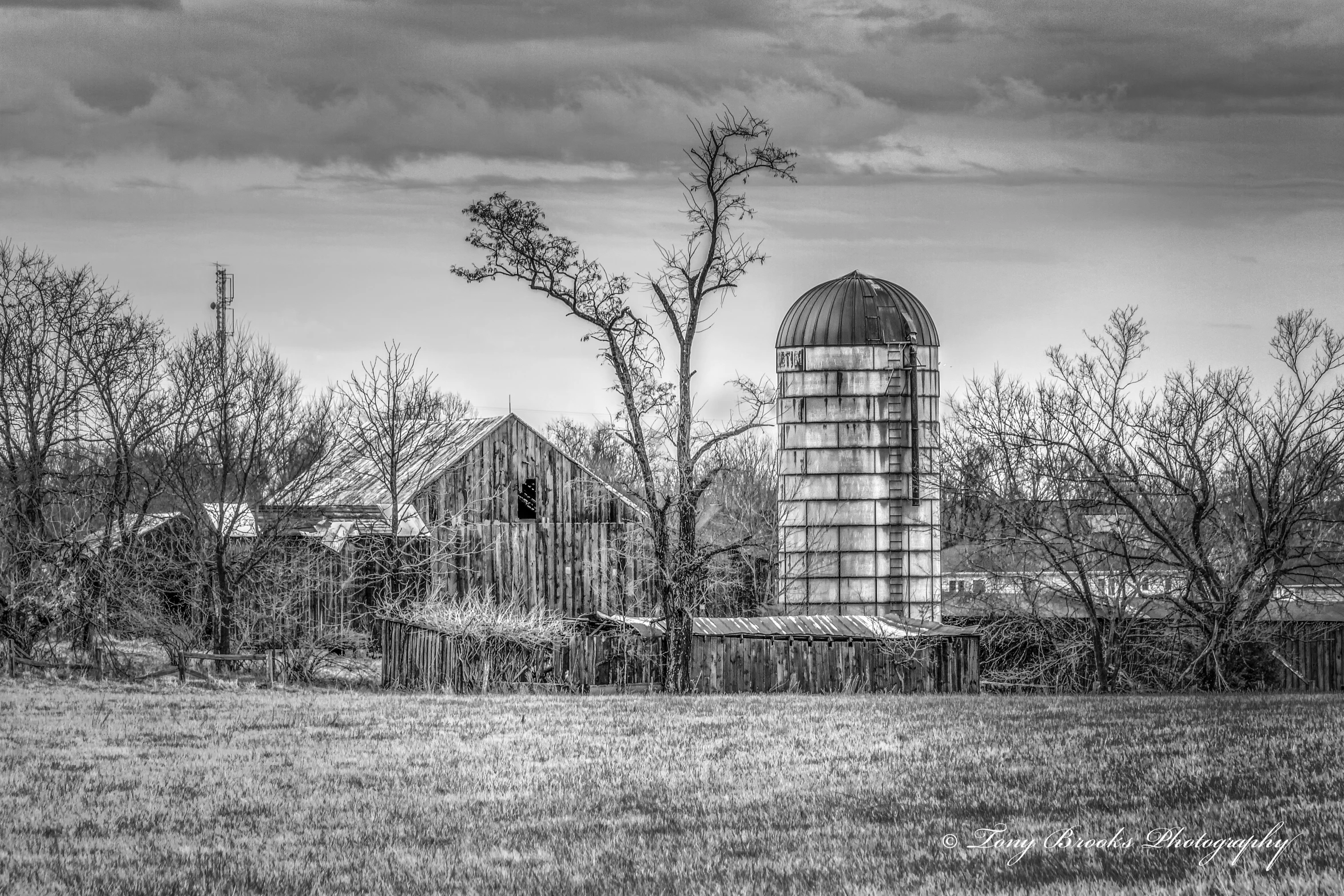 an old barn and silo in the distance