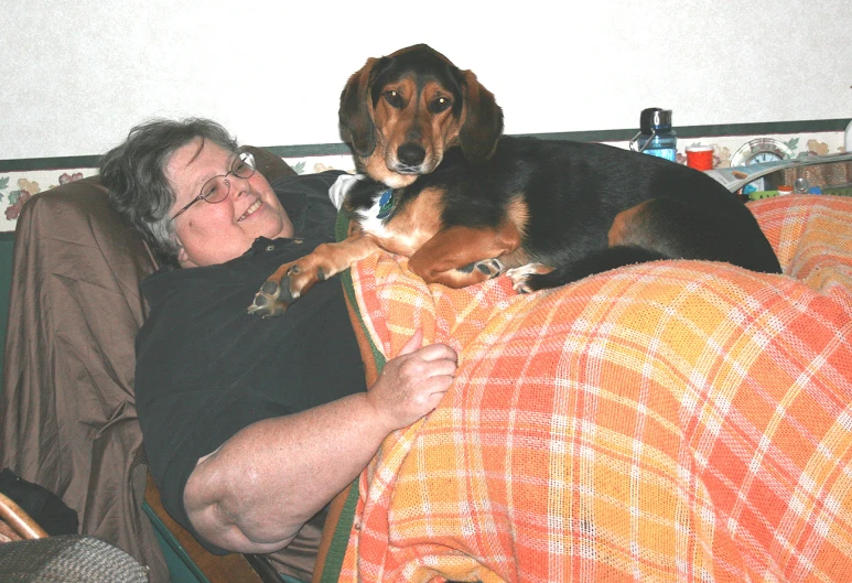 a woman is laying in bed with a dog on her back