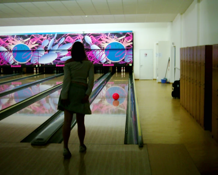 there is a woman that is standing at the end of a bowling alley