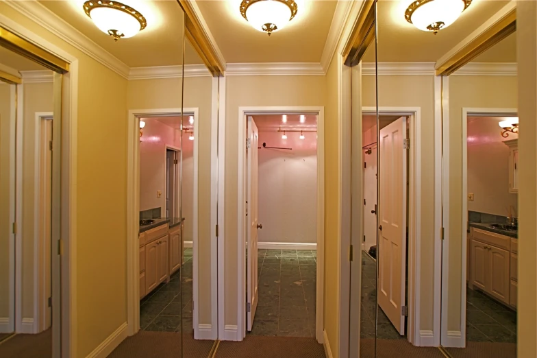 mirrors in a hallway are reflecting a bathroom and another room