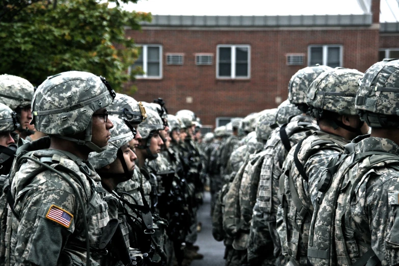 military men in camo standing outside looking at soing