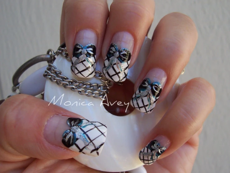 a hand with a manicure with blue, black and white designs on it