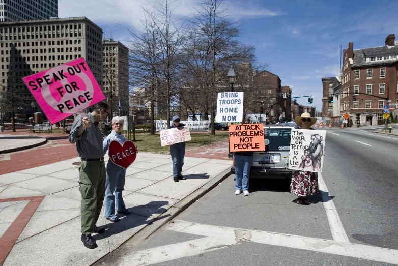 people are holding signs while they stand on the side of the road