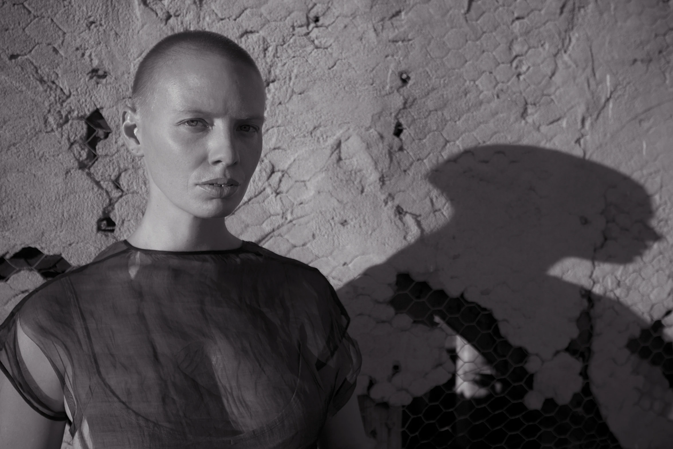 a woman standing in front of a wall with a bald head