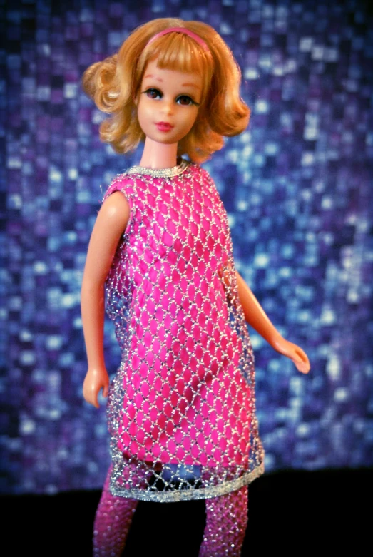 a doll in a pink dress on a blue background