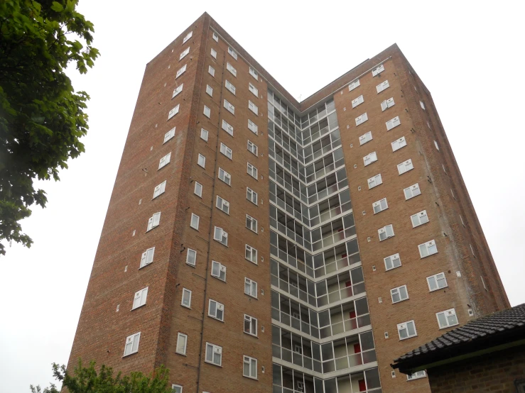 a tall red brick building sitting next to a tree