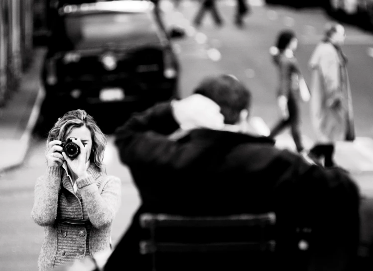 a woman is taking pictures with her camera as a man sits on the side walk