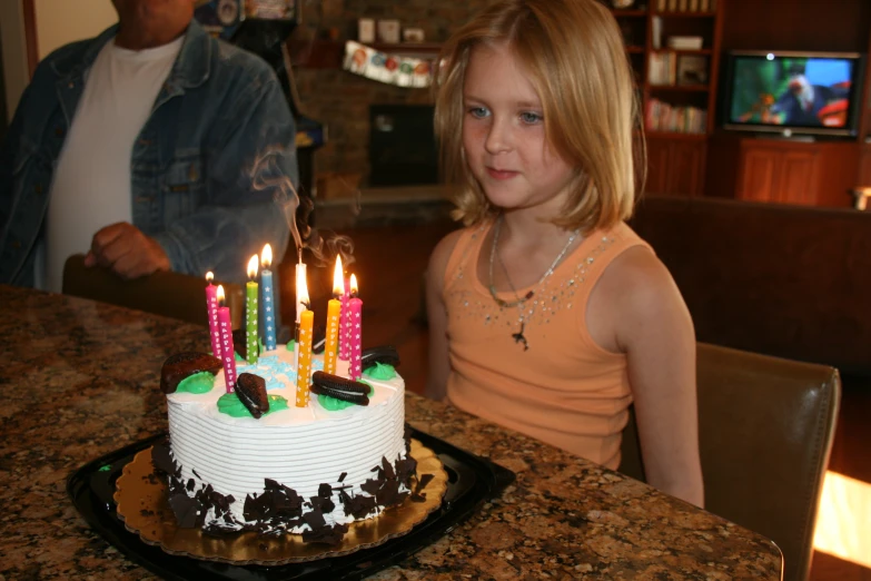 a  sitting in front of a cake with candles lit