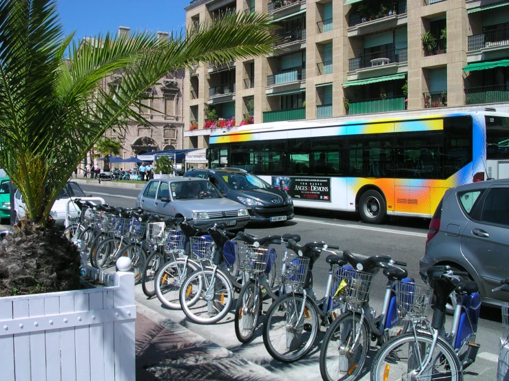 a city bus is driving past a line of bicycles