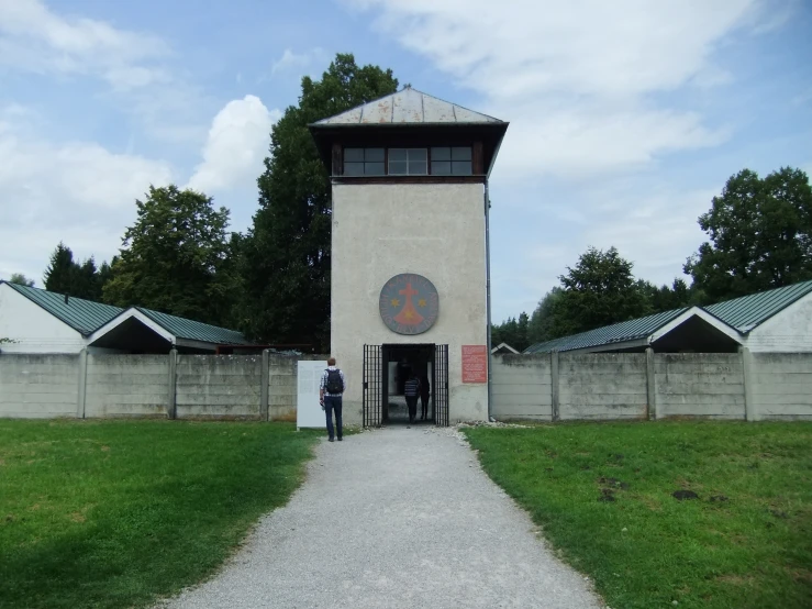 a walkway leads up to a tower with clock and symbols