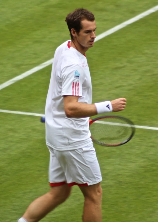 a man walking on grass carrying a tennis racket