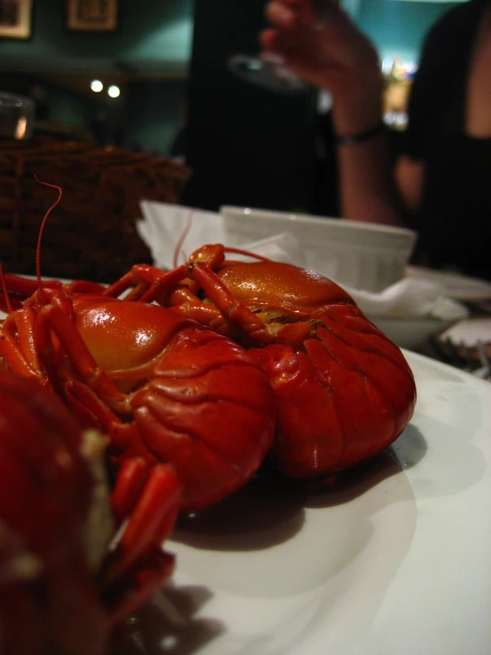 there are some lobsters on the plate with someone holding a glass