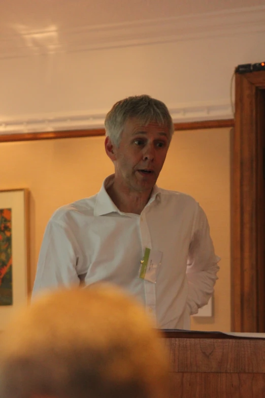 a man with his hands clasped talking on a stage