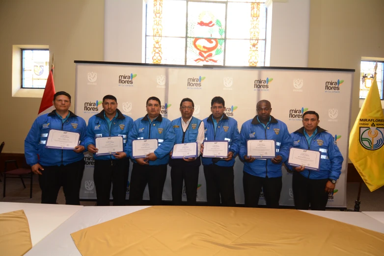 seven men in blue jackets with white paper