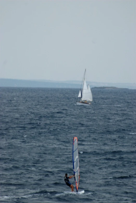 a sailboat with a man riding on top in the water