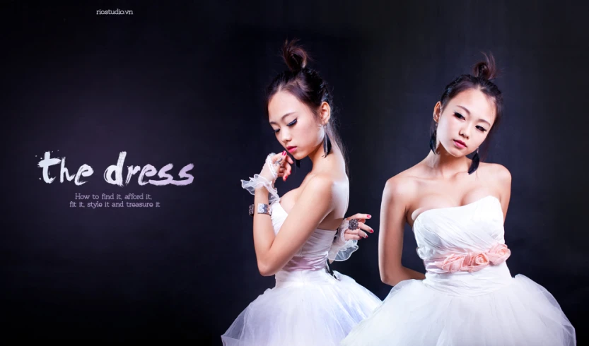 two young ladies wearing white dresses in front of a black wall